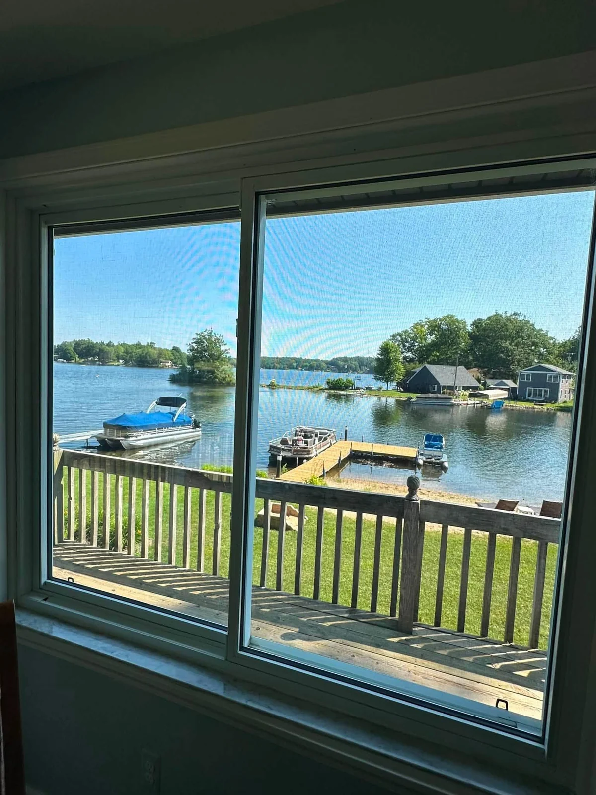 A pair of home windows overlooking a deck, docks, and a lake